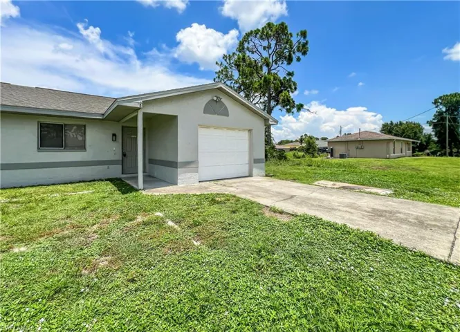 Attached single-car garage with a concrete driveway, covered entryway, and a shingle roof
