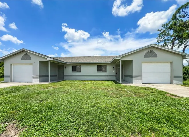 Duplex property featuring a stucco exterior, attached garages, and a paved driveway