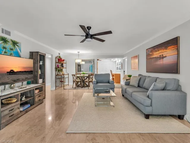 Living room with crown molding, ceiling fan, and tile patterned floors