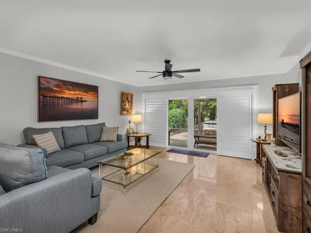 Living room with crown molding, light tile patterned floors, and ceiling fan