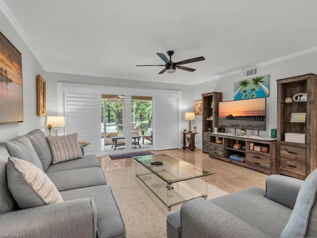 Living room with light hardwood / wood-style flooring, ceiling fan, and ornamental molding