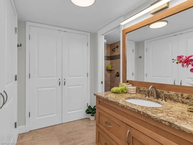 Bathroom with tiled shower, vanity, and tile floors