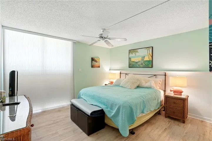 Bedroom with wood finished floors, a textured ceiling, and a ceiling fan - Virtually Edited Image