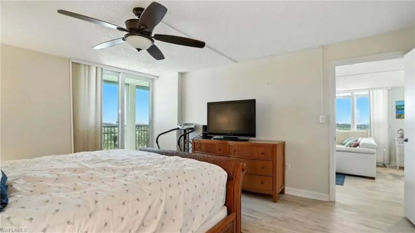 Bedroom featuring access to outside, a ceiling fan, wood finished floors, and a textured ceiling - Virtually Edited Image