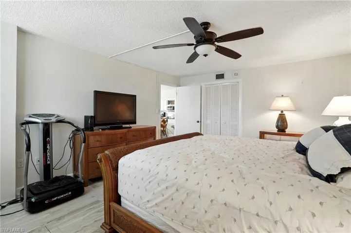 Bedroom featuring a closet, a textured ceiling, light wood-style floors, and a ceiling fan - Virtually Edited Image