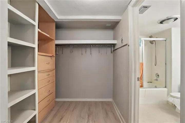 Walk in closet featuring light wood finished floors - Virtually Edited Image