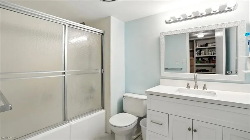 Bathroom featuring vanity, bath / shower combo with glass door, and a closet - Virtually Edited Image