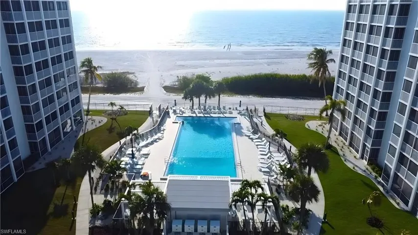 Community pool featuring view of water and beach - Virtually Edited Image