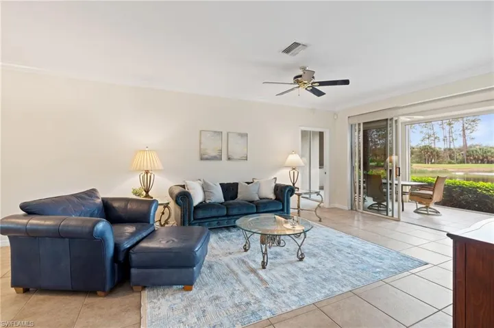 Tiled living room with ceiling fan and crown molding