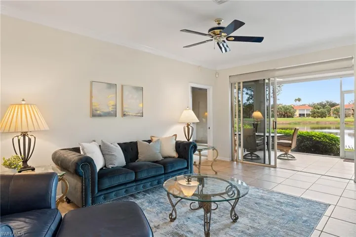 Living room with ceiling fan, light tile patterned floors, and ornamental molding