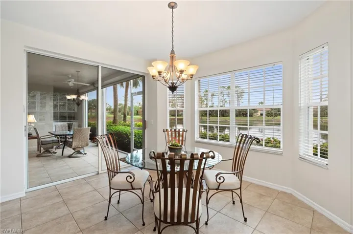 Dining area featuring light tile patterned floors and ceiling fan with notable chandelier