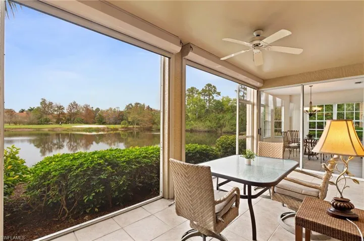 Sunroom / solarium with ceiling fan with notable chandelier and a water view