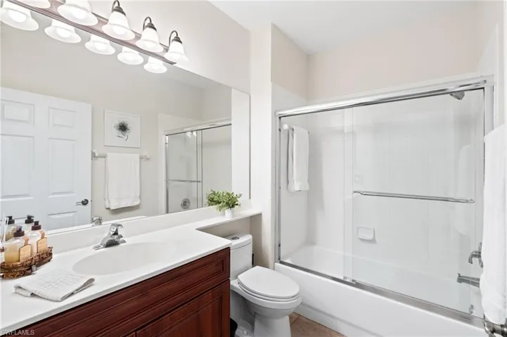 Full bathroom featuring bath / shower combo with glass door, toilet, and vanity