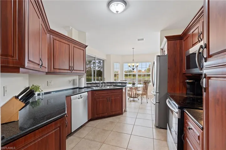 Kitchen featuring a notable chandelier, pendant lighting, sink, stainless steel appliances, and light tile patterned floors