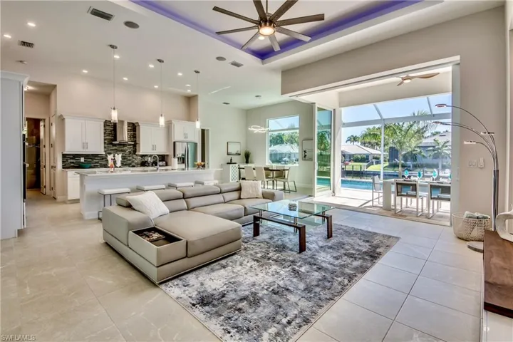 Living area with ceiling fan, a high ceiling, a sunroom, a raised ceiling, and recessed lighting