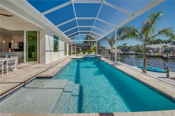 View of pool with a sunroom, a patio, a lanai, a pool with connected hot tub, and a water view