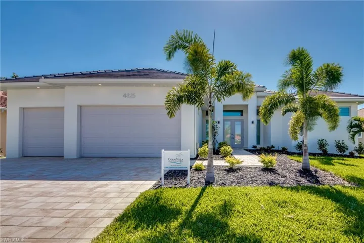 View of front of property featuring an attached garage, decorative driveway, stucco siding, a front lawn, and french doors