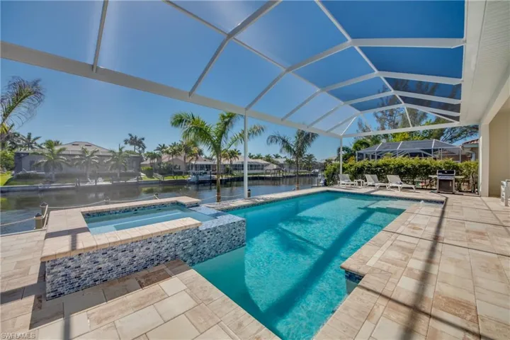 View of pool with a patio area, a sunroom, a water view, a pool with connected hot tub, and a lanai