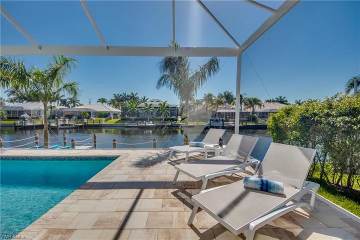 Outdoor pool with a water view, a patio area, a residential view, and glass enclosure