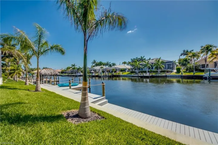 Dock with a water view, a residential view, and a lawn