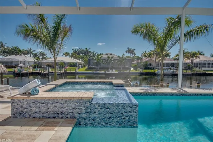 View of pool with a water view, a pool with connected hot tub, a residential view, and a boat dock