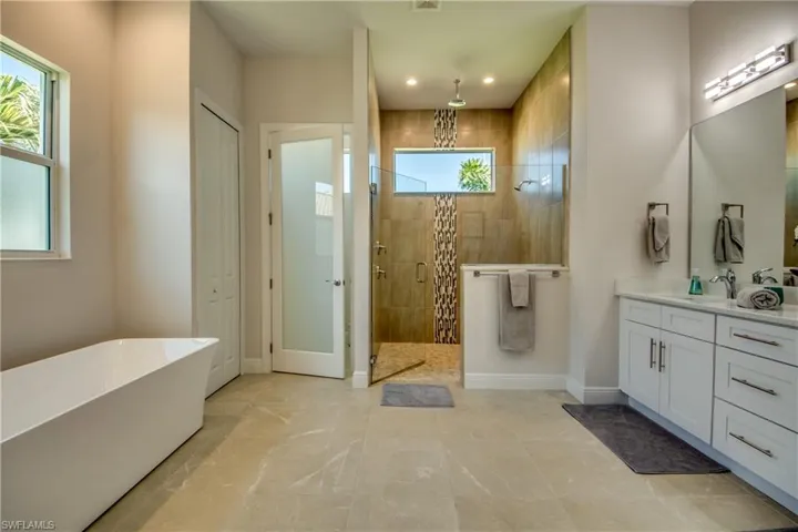 Full bathroom with a closet, a shower stall, a freestanding bath, and vanity