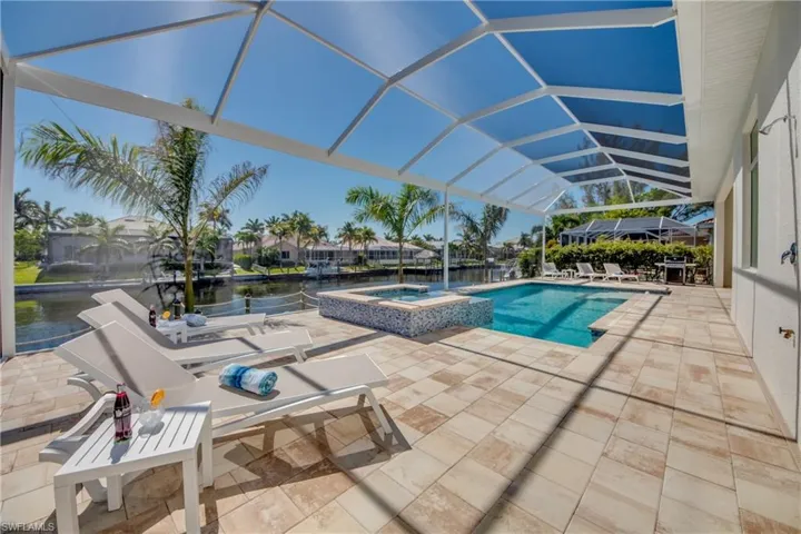 View of swimming pool with a sunroom, a patio, a water view, a pool with connected hot tub, and glass enclosure