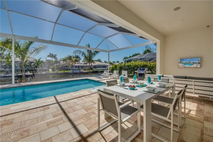 Swimming pool featuring a patio area, a sunroom, a lanai, outdoor dining space, and a grill