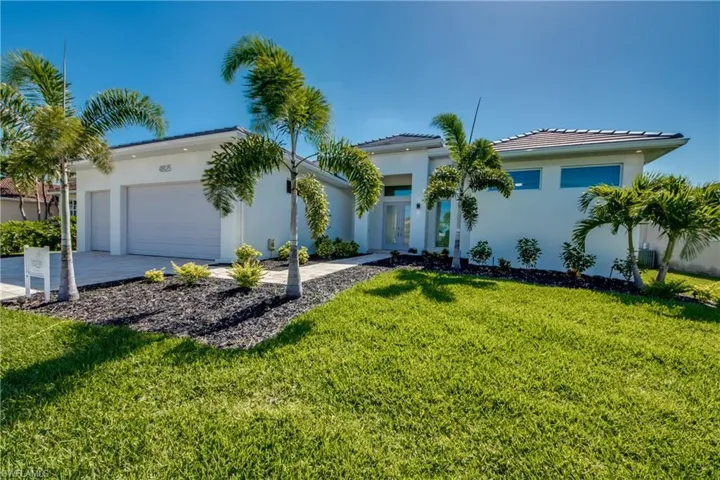View of front of house featuring an attached garage, stucco siding, a front lawn, concrete driveway, and a tiled roof