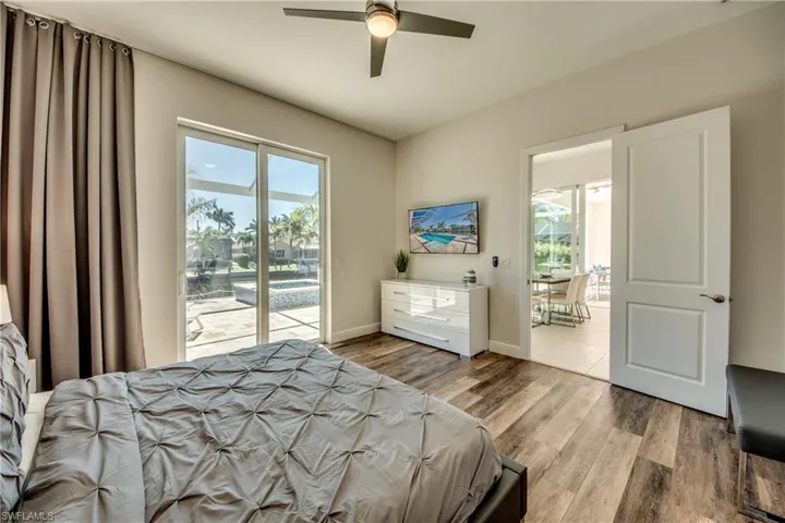 Bedroom with multiple windows, a ceiling fan, light wood-style floors, and access to outside