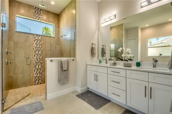 Full bath featuring double vanity, a shower stall, and light tile patterned flooring