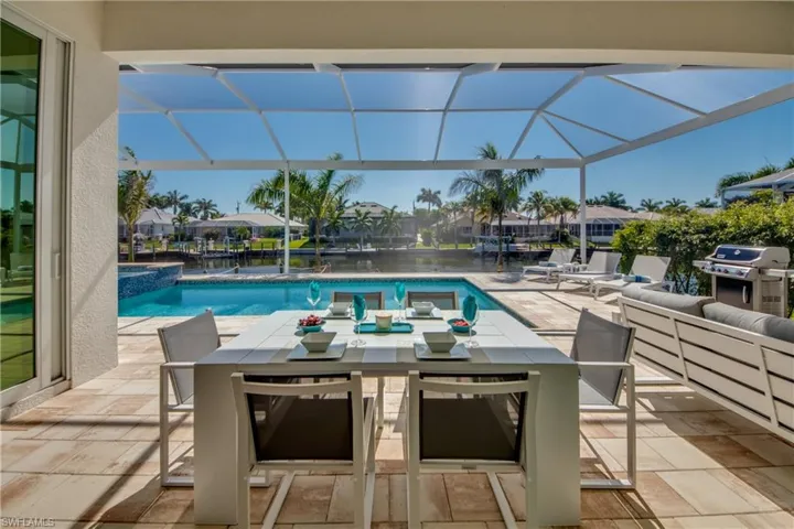 View of swimming pool with a sunroom, outdoor dining space, a patio, glass enclosure, and a grill