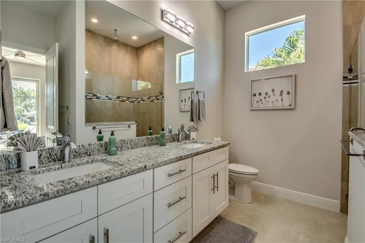 Full bath with walk in shower, double vanity, and light tile patterned floors