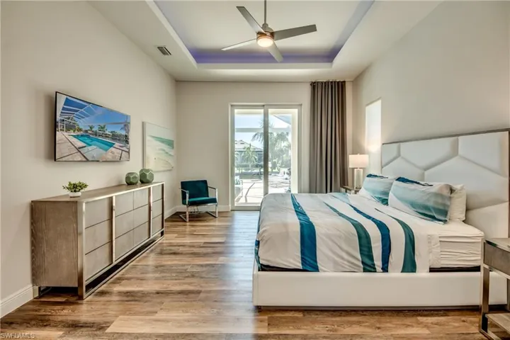 Bedroom featuring a raised ceiling, access to outside, a ceiling fan, and light wood-type flooring