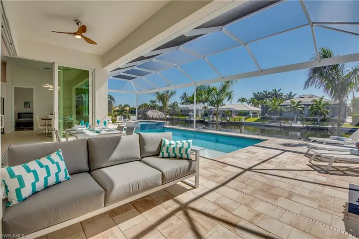 View of pool featuring a sunroom, a patio, glass enclosure, a pool with connected hot tub, and a water view