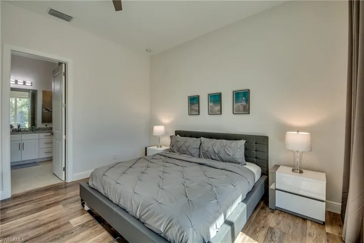 Bedroom with light wood-style floors, a ceiling fan, and ensuite bathroom
