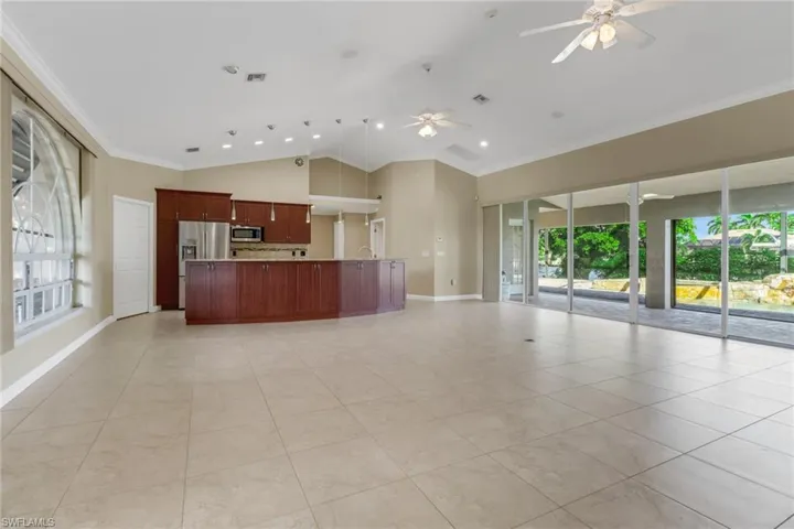 Unfurnished living room with light tile patterned flooring, lofted ceiling, a healthy amount of sunlight, and crown molding