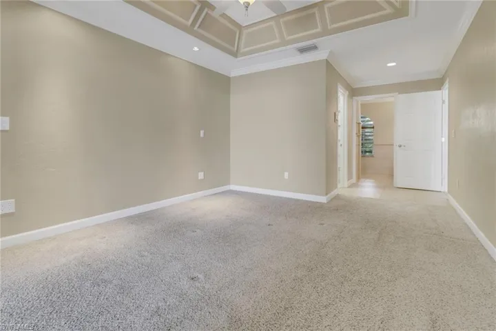 Empty room featuring crown molding, ceiling fan, and light colored carpet