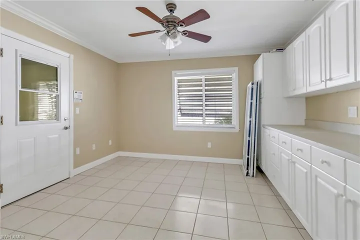 Kitchen with ornamental molding, white cabinets, light tile patterned floors, and ceiling fan