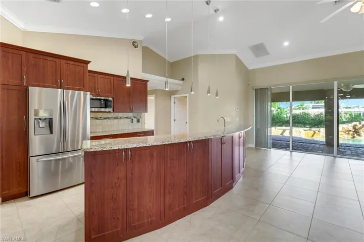 Kitchen featuring light stone counters, ornamental molding, tasteful backsplash, decorative light fixtures, and appliances with stainless steel finishes