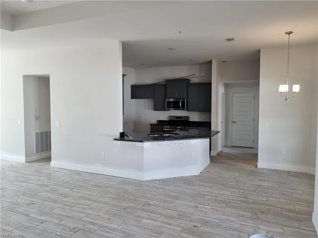 Kitchen with kitchen peninsula, a chandelier, light hardwood / wood-style floors, and appliances with stainless steel finishes