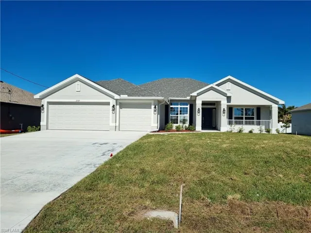 Ranch-style home with a front lawn, covered porch, and a garage