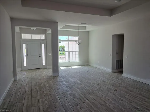 Entryway with an inviting chandelier, a tray ceiling, and dark wood-type flooring