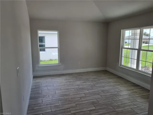 Spare room with light hardwood / wood-style flooring, a wealth of natural light, and vaulted ceiling