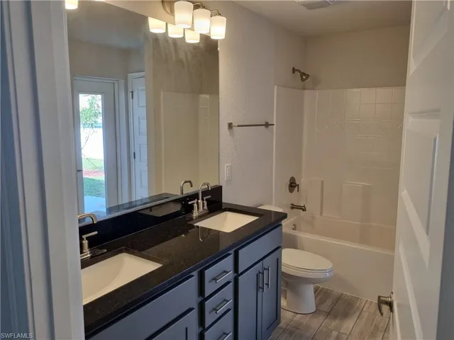 Full bathroom featuring vanity, wood-type flooring,  shower combination, and toilet