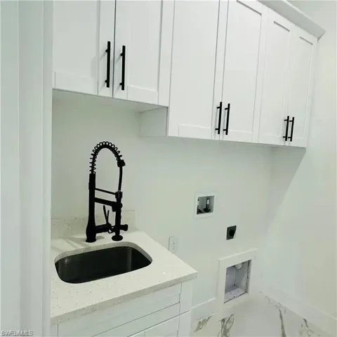 Laundry area featuring white shaker-style cabinetry with matte black hardware, a quartz countertop, and a black gooseneck faucet over a built-in utility sink