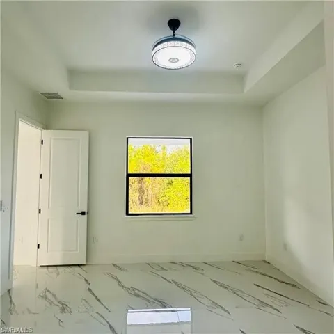 Room featuring a large window, tray ceiling, and a contemporary ceiling fixture