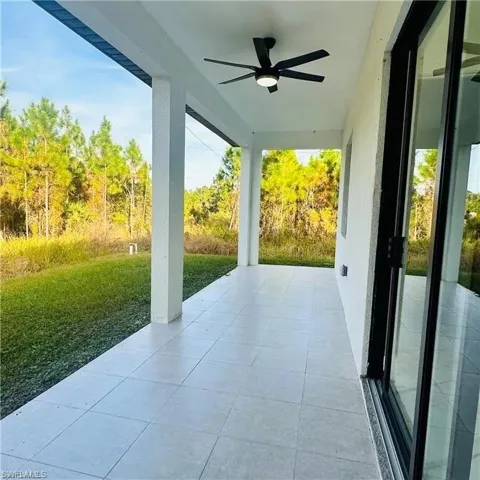 Covered outdoor patio featuring light-toned tile flooring and a black ceiling fan with integrated lighting