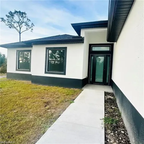 Modern exterior featuring a prominent black-framed entry door with a transom window