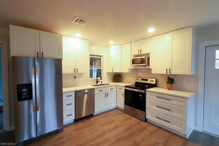 Kitchen with white cabinetry, appliances with stainless steel finishes, sink, and light wood-type flooring